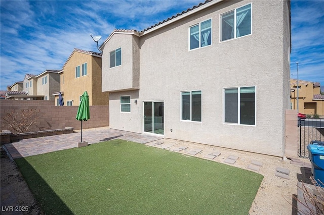 back of house with a patio area, a lawn, a fenced backyard, and stucco siding