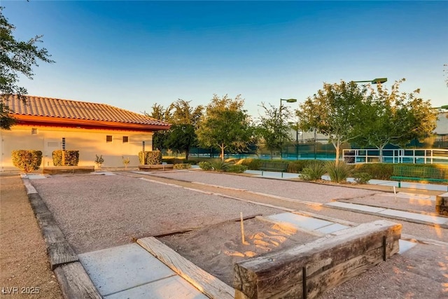 exterior space featuring a tennis court and fence