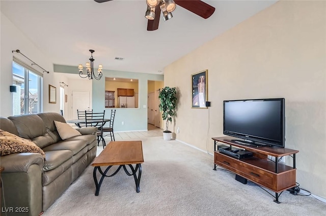 living area featuring light colored carpet, visible vents, baseboards, and ceiling fan with notable chandelier