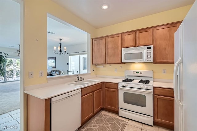 kitchen featuring white appliances, brown cabinets, a sink, and light tile patterned flooring