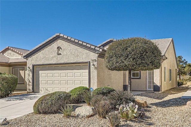 ranch-style house featuring a garage, a tile roof, concrete driveway, and stucco siding