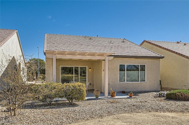 rear view of house with a tile roof and stucco siding