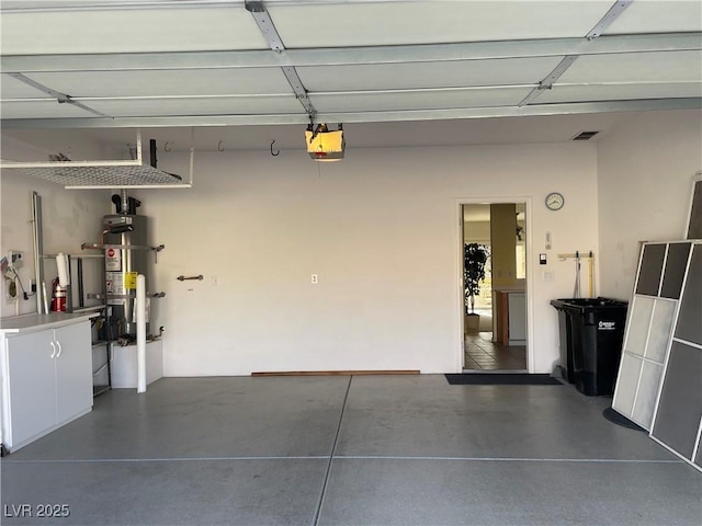 garage featuring strapped water heater, visible vents, and a garage door opener