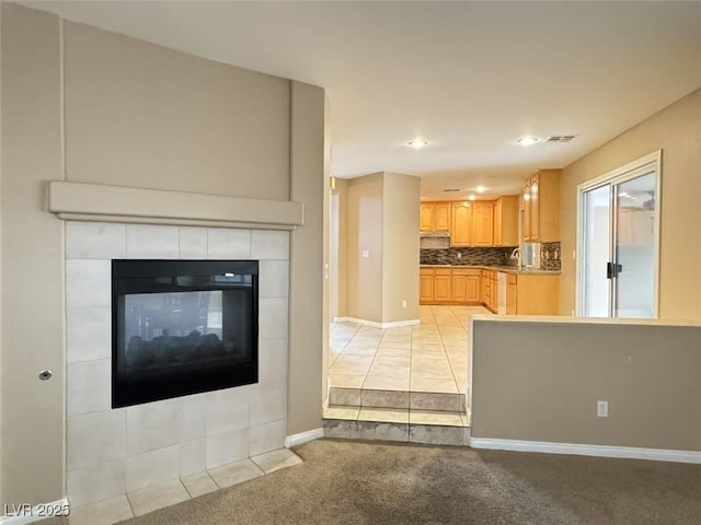 kitchen with light carpet, visible vents, baseboards, backsplash, and light brown cabinetry