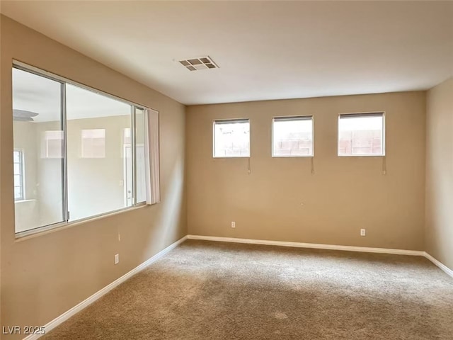 carpeted spare room featuring baseboards and visible vents