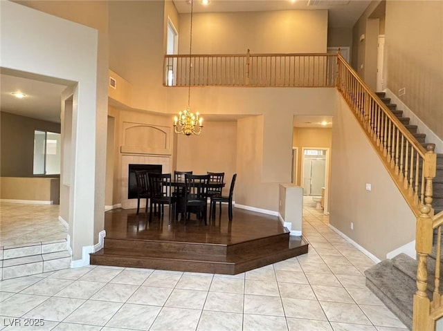 tiled dining room featuring a chandelier, baseboards, stairway, and a high ceiling