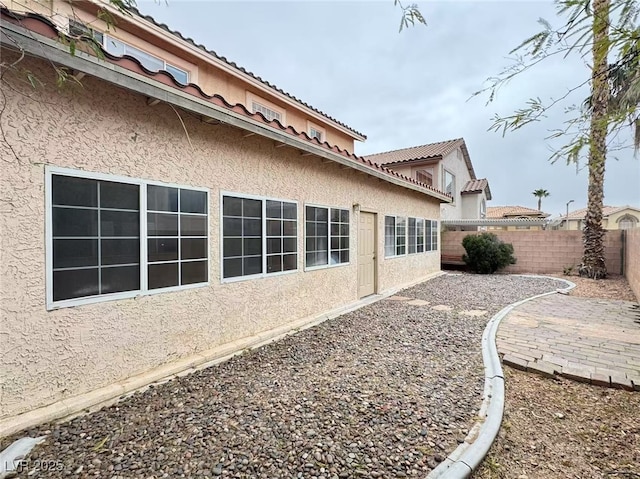 view of home's exterior featuring a patio area, a tile roof, fence, and stucco siding