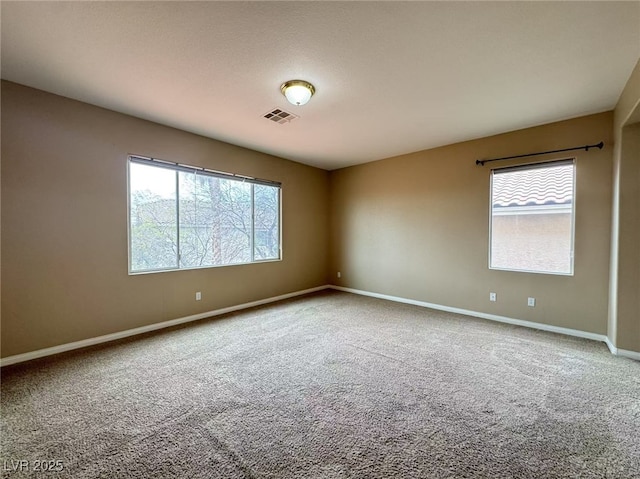 empty room featuring carpet floors, baseboards, and visible vents