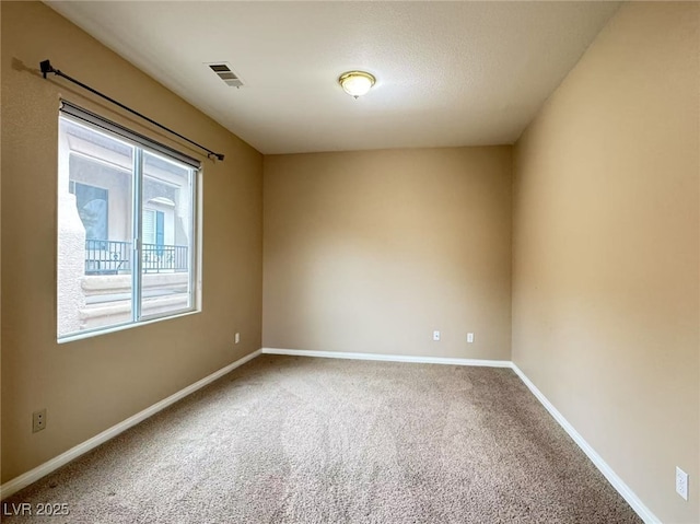 empty room with carpet, visible vents, and baseboards