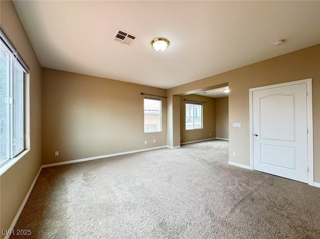 unfurnished room featuring baseboards, visible vents, and light colored carpet