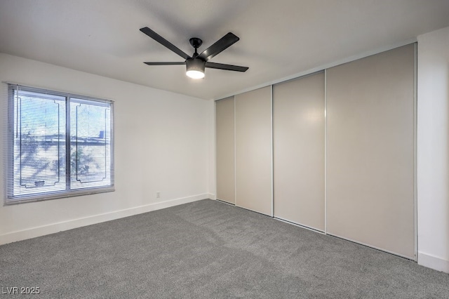 carpeted spare room with a ceiling fan and baseboards