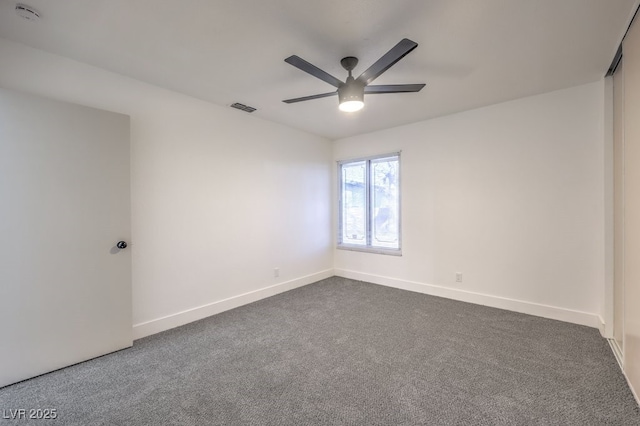 unfurnished room featuring a ceiling fan, dark colored carpet, visible vents, and baseboards