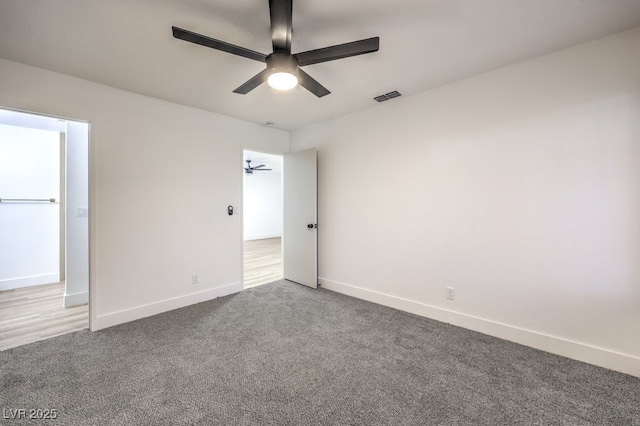 carpeted spare room with baseboards, visible vents, and a ceiling fan