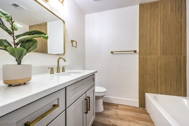 full bath with toilet, a bathing tub, wood finished floors, vanity, and visible vents