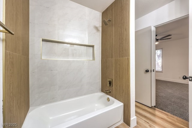 bathroom featuring ceiling fan,  shower combination, wood finished floors, and baseboards