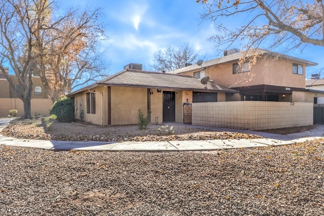 view of front of house featuring central AC, a fenced front yard, and stucco siding