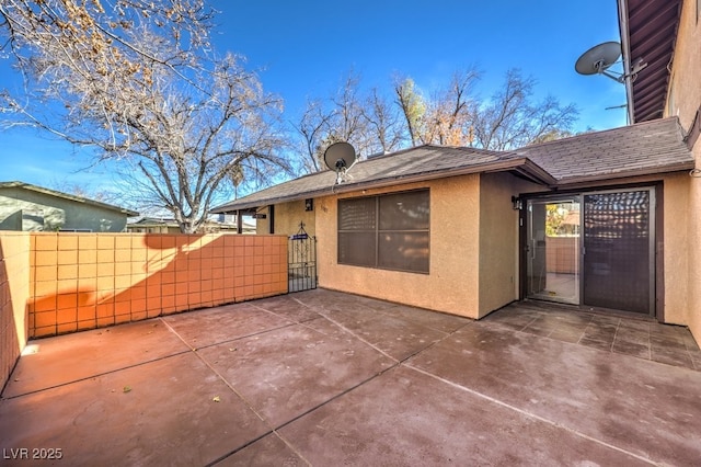 exterior space featuring a patio, roof with shingles, fence, and stucco siding