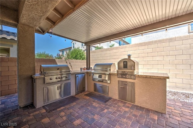 view of patio with a grill, an outdoor kitchen, and a fenced backyard