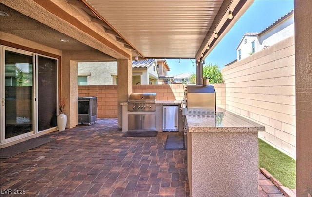 view of patio featuring a grill, fence, and exterior kitchen