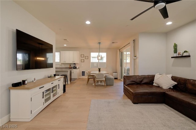 living room featuring light wood-style floors, ceiling fan, baseboards, and recessed lighting