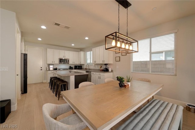 dining space with light wood-type flooring, visible vents, and recessed lighting