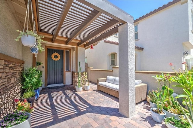 doorway to property featuring a pergola, a patio area, a tile roof, and stucco siding