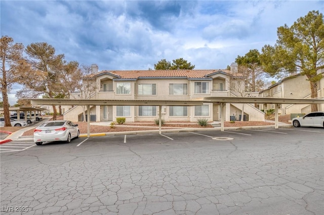 5265 Caspian Springs Dr Unit 201, Las Vegas, NV 89120 - view of front of property featuring a tile roof, covered parking, a chimney, and stucco siding