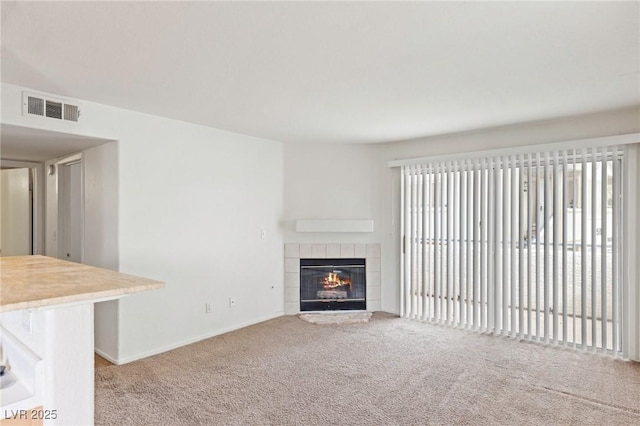 unfurnished living room featuring carpet, a tile fireplace, and visible vents