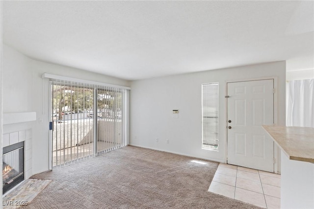 5265 Caspian Springs Dr Unit 201, Las Vegas, NV 89120 - unfurnished living room featuring a tile fireplace, light carpet, and light tile patterned floors