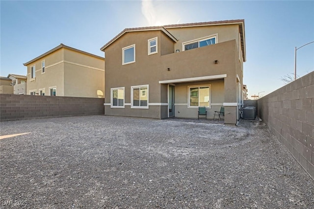 rear view of property featuring cooling unit, a fenced backyard, and stucco siding