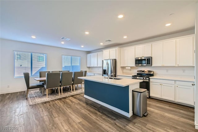 kitchen featuring light countertops, appliances with stainless steel finishes, dark wood-type flooring, and visible vents