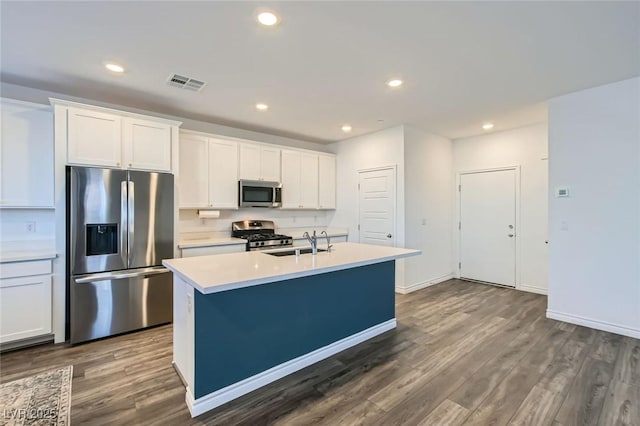 kitchen featuring a kitchen island with sink, stainless steel appliances, dark wood-style flooring, a sink, and visible vents