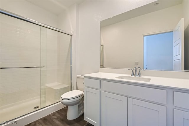 full bath with a stall shower, vanity, toilet, and wood finished floors