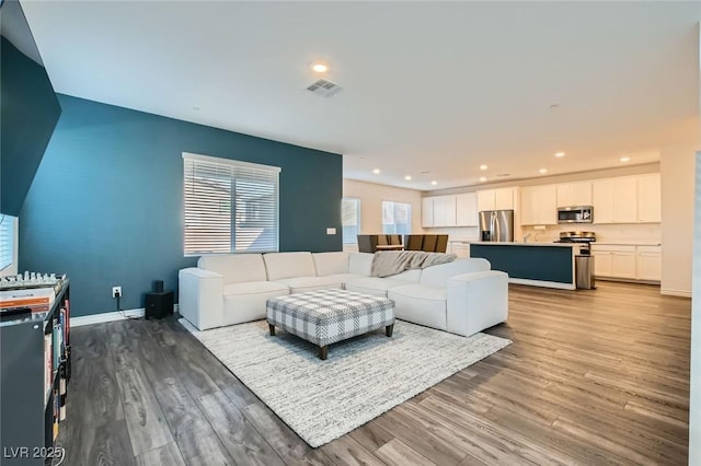 living room featuring light wood-style floors, baseboards, visible vents, and recessed lighting