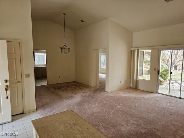 unfurnished dining area with a notable chandelier, high vaulted ceiling, light tile patterned flooring, and light colored carpet