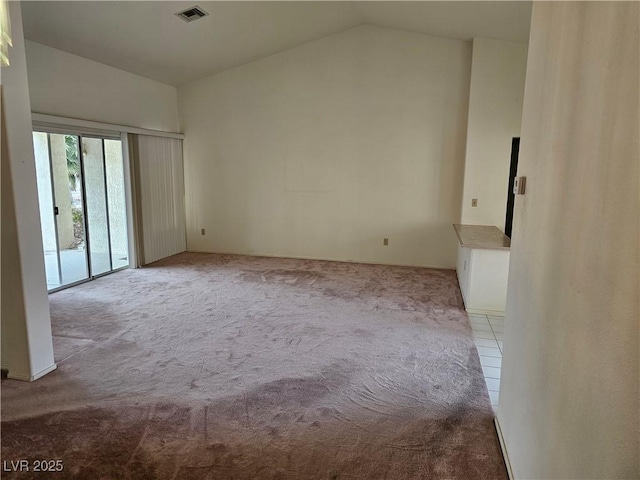 carpeted empty room with visible vents and vaulted ceiling