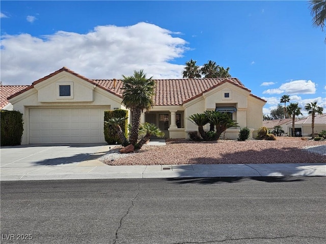 mediterranean / spanish-style home featuring driveway, an attached garage, a tiled roof, and stucco siding