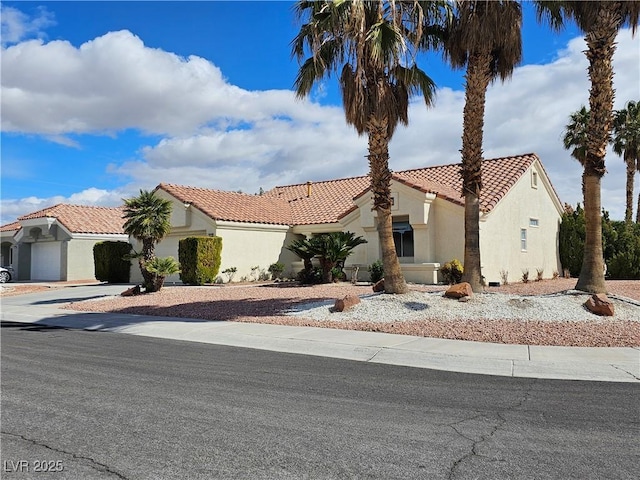 view of front facade with driveway, a tile roof, and stucco siding