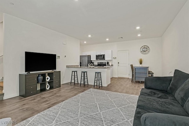 living area featuring recessed lighting, visible vents, baseboards, and wood finished floors