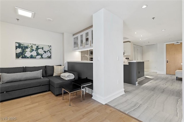 living area with light wood-style flooring, baseboards, and recessed lighting