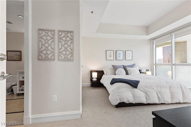 bedroom with carpet, a tray ceiling, and baseboards