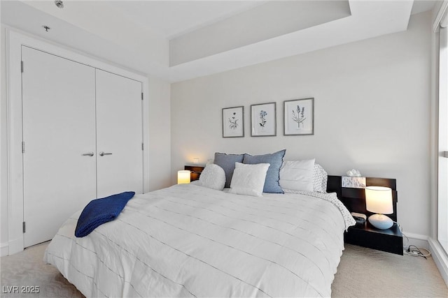 bedroom with a closet, carpet, and a raised ceiling