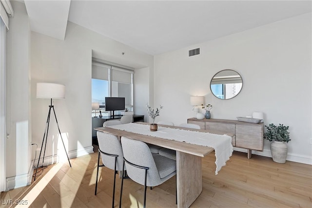 dining area featuring light wood-style floors, plenty of natural light, and visible vents