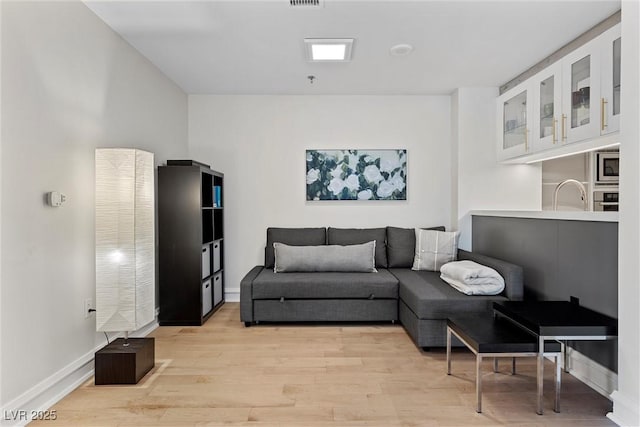 living room featuring light wood-style floors, visible vents, and baseboards