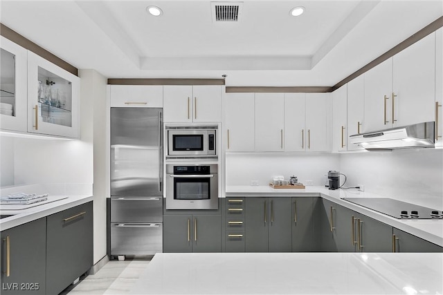 kitchen featuring built in appliances, under cabinet range hood, visible vents, white cabinets, and light countertops