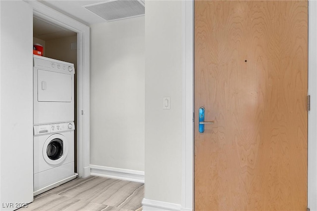 laundry room featuring baseboards, visible vents, stacked washer / dryer, and wood finished floors