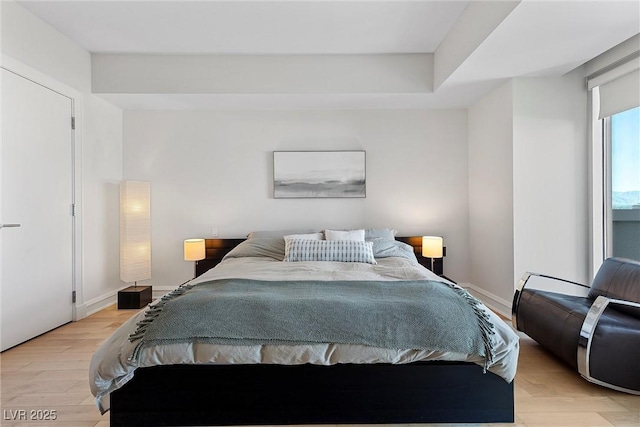 bedroom with light wood finished floors and baseboards