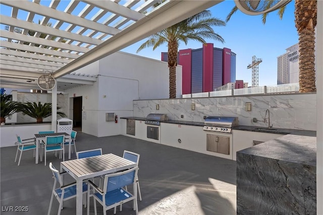 view of patio with exterior kitchen, outdoor dining area, a sink, and area for grilling