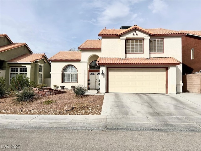 mediterranean / spanish-style home with driveway, a tiled roof, an attached garage, and stucco siding