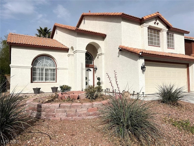 mediterranean / spanish-style home featuring driveway, an attached garage, a tile roof, and stucco siding